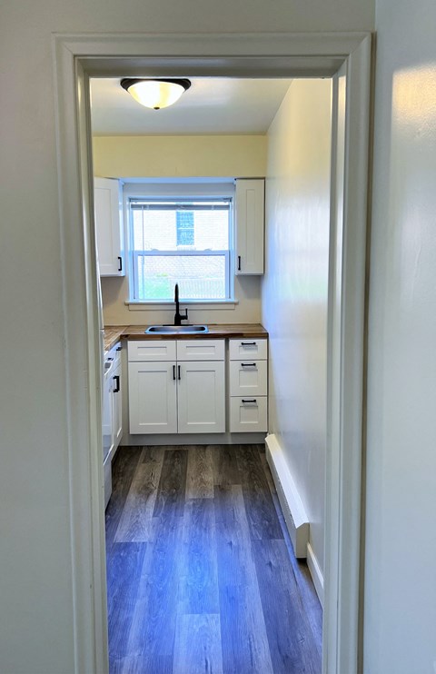 an empty kitchen with white cabinets and a window